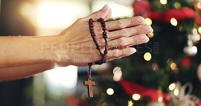 Buy stock photo Person, hands and christian praying with cross for christmas miracle, faith or religion in home. Closeup, christianity and prayer with beads for Jesus christ, december holiday or holy tradition