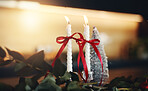 Christmas, decoration and ribbon with candles in home for festive ambience or holiday atmosphere. December, season or winter with bow and burning wick in apartment for celebration or tradition