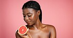 Black woman, skincare and vitamin C with grapefruit in studio for health on a pink background. Female person, model and glow with natural organic fruit for detox, beauty or nutrition on mockup space
