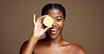 Happy, black woman and portrait with lemon for skincare or health on a brown studio background. Face, female person or model with smile or natural organic fruit for vitamin C, diet or citrus acid