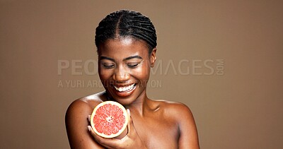 Buy stock photo Beauty, happy and black woman with grapefruit in studio for natural, organic or facial glow routine. Dermatology, skincare and African person with citrus for face brightening by brown background.