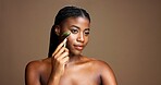 Beauty, skincare and woman with jade roller in studio for depuffing, facial massage and skin glow. Mockup, black girl or cosmetics tool on brown background for lymphatic drainage, routine or radiance