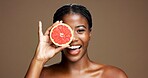 Happy, black woman or portrait with grapefruit for health or skincare on a brown studio background. Face, female person or model with smile or natural organic fruit for vitamin C, diet or fiber