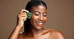 Facial massage, gua sha and smile with black woman on studio space for dermatology or wellness. Beauty, jade stone and skincare with African model on banner to relax skin for antiaging routine