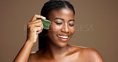 Buy stock photo Facial massage, gua sha and smile with black woman on studio space for dermatology or wellness. Beauty, jade stone and skincare with African model on banner to relax skin for antiaging routine