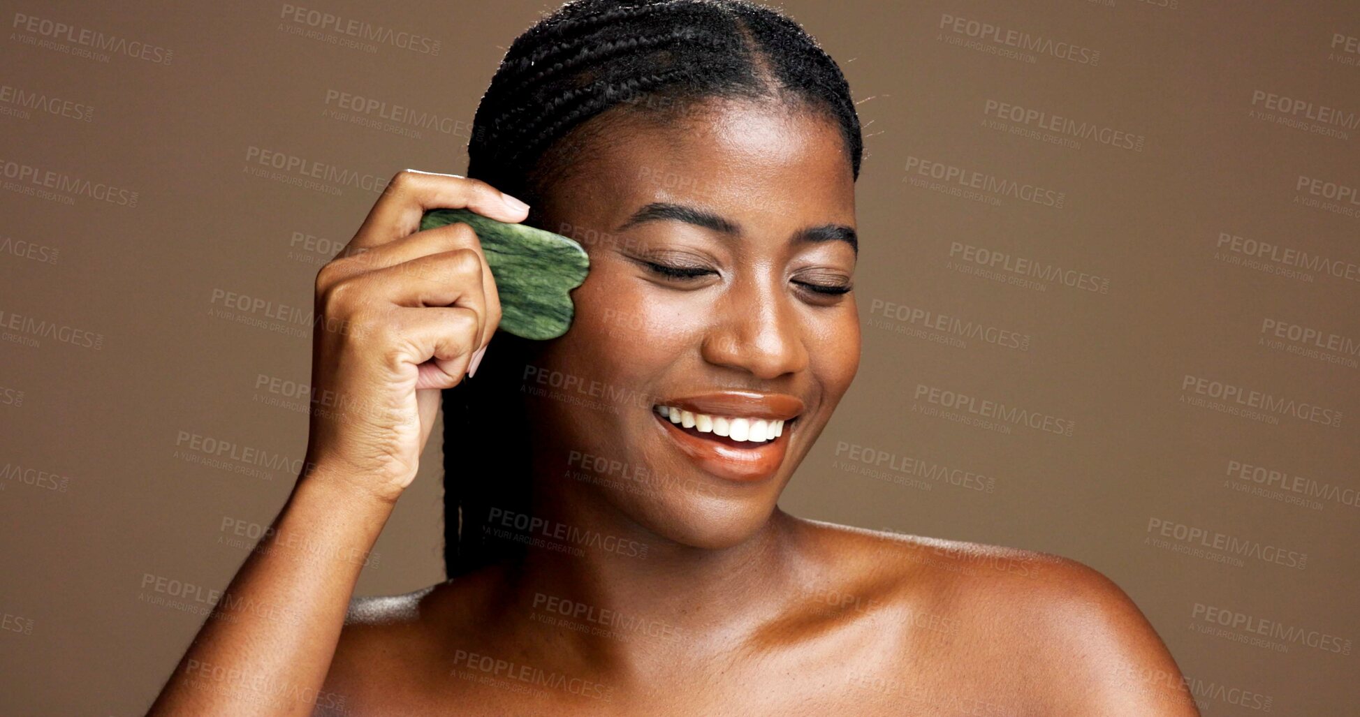 Buy stock photo Facial massage, gua sha and smile with black woman on studio space for dermatology or wellness. Beauty, jade stone and skincare with African model on banner to relax skin for antiaging routine