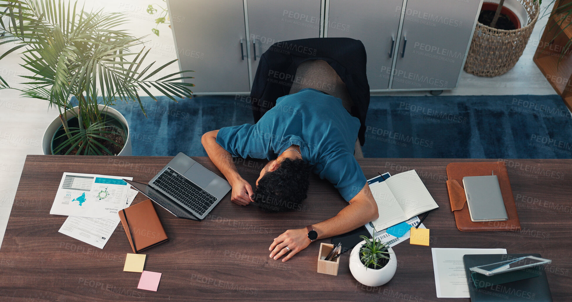 Buy stock photo Burnout, sleeping and tired with man on desk in office for deadline on demographics project. Documents, fatigue and laptop with overworked business person lying on wooden table at work from above