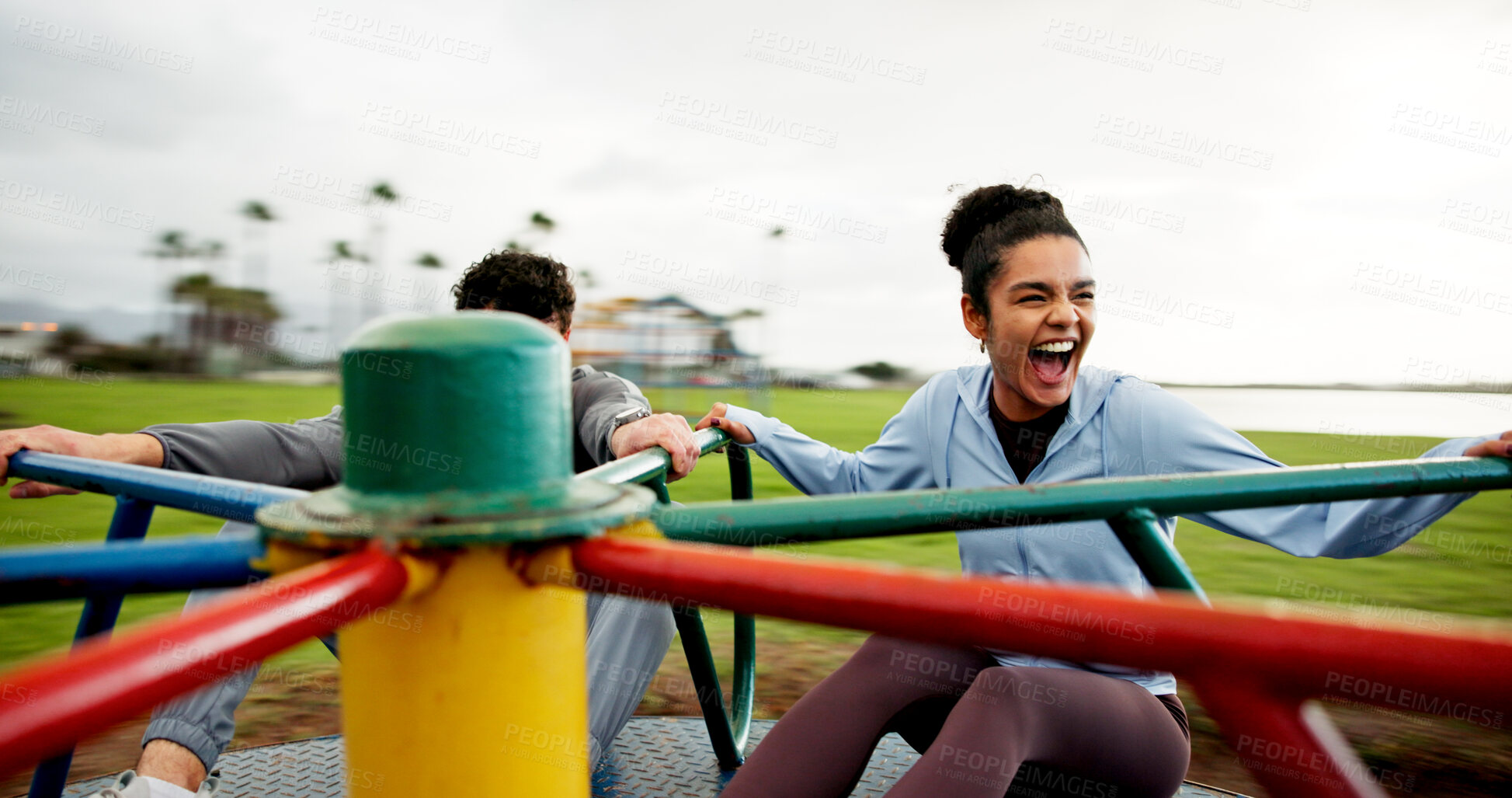 Buy stock photo People, laughing and spinning on roundabout at park for workout break, adrenaline or freedom. Fitness, excited or couple with energy on carousel on playground for playing together or rest from cardio