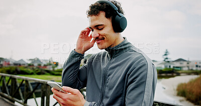Buy stock photo Headphones, fitness or man on bridge with phone for workout, tracking exercise or song. Lake, smile or athlete runner on mobile app in city for running progress, music playlist and podcast audio