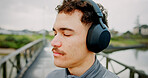 Outdoor, calm and man with headphones, listening and streaming of playlist on break, athlete or web. Online, mindfulness and person with tech for music, runner and song for peace, bridge or city