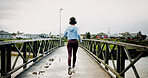 Running, headphones and woman on bridge for exercise, marathon training and workout for endurance. Sports, runner and back of person listening to music in winter for performance, cardio and fitness