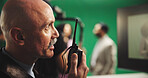 Man, director and radio with green screen for action, scene or instruction in production studio. Male person, producer or manager talking with signal or cut for take, cue or special effects in set