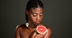 Black woman, grapefruit or beauty with skincare in studio for skin detox on a dark background. Female person, model and natural organic fruit for antioxidant, vitamin C or body health on mockup space