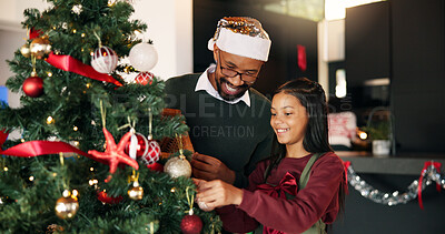 Buy stock photo Father, child and Christmas tree decoration in home for festive tradition, holiday or bonding. Help, African people and hang bauble ornaments in lounge for xmas aesthetic, creativity and celebration