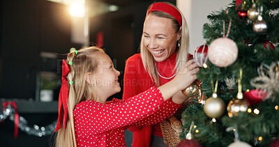 Buy stock photo Christmas tree, mother and daughter with ball for decoration for festive holiday, tradition or help. Girl child, woman and ornament in family home for celebration, happiness and laugh for bonding