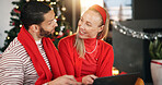 Christmas, home and couple with tablet, talking and search for presents, festive or bonding together. Tradition, tech or man with woman, discussion or online entertainment with holiday season or Xmas