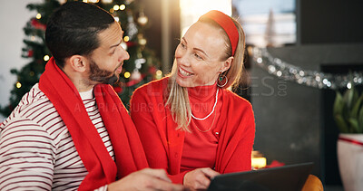 Buy stock photo Christmas, home and couple with tablet, talking and search for presents, festive or bonding together. Tradition, tech or man with woman, discussion or online entertainment with holiday season or Xmas