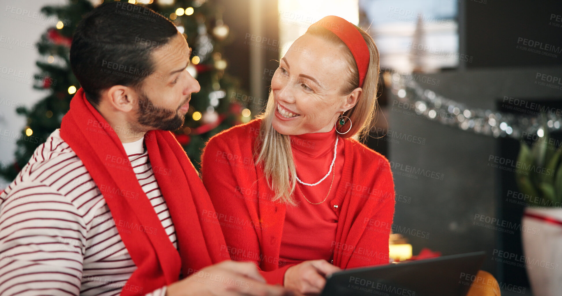 Buy stock photo Christmas, home and couple with tablet, talking and search for presents, festive or bonding together. Tradition, tech or man with woman, discussion or online entertainment with holiday season or Xmas