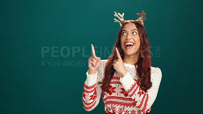 Buy stock photo Christmas, excited woman and pointing up to space in studio for advertising, marketing or mockup. Laugh, offer or person with show promo, xmas discount or festive sale on holiday on green background