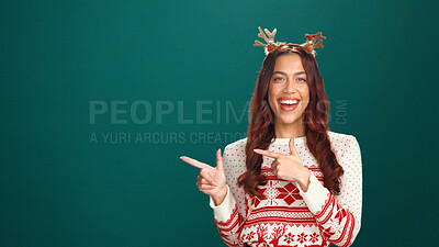 Buy stock photo Christmas, woman and pointing to offer in studio for advertising, announcement or mockup. Portrait, person and show space for promotion, xmas discount and laugh for holiday sale on green background