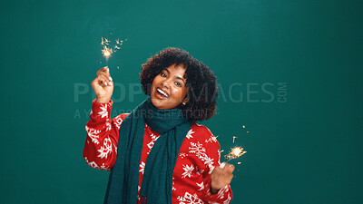 Buy stock photo Christmas, portrait and excited woman with sparklers in studio for holiday celebration with space. African person, happy and fireworks for xmas, festive season and laughing on green background