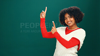 Buy stock photo Christmas, woman and pointing up to space in studio for advertising, mockup or coming soon. Portrait, smile and African person with promotion offer, xmas discount and festive sale on green background