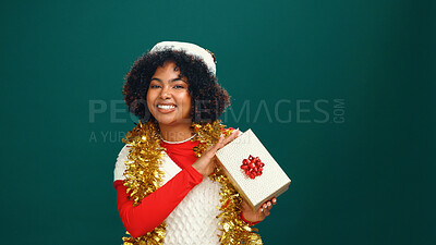 Buy stock photo Santa hat, portrait and black woman with present in studio for Christmas tradition, festive or celebration. Happy, holiday and African female person with gift box for xmas event by green background.