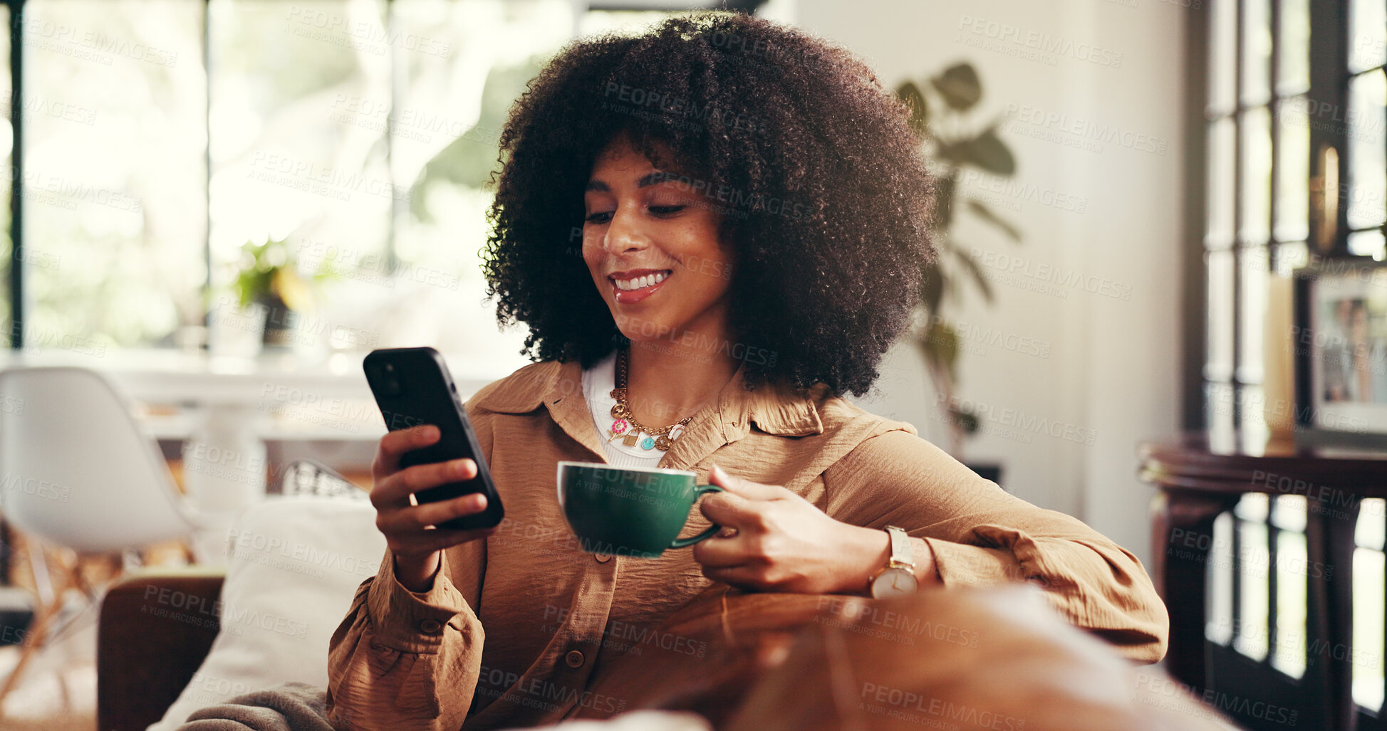 Buy stock photo Woman, coffee and phone on sofa for social media, connectivity and text message with smile. African girl, mobile and drink in home for communication, status update and forum discussion on internet