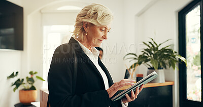 Buy stock photo Business woman, tablet and lobby at hotel for trip schedule, contact or typing at luxury accommodation. Mature person, tech or scroll with app notification in hallway, travel and hospitality at lodge