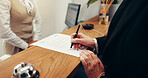 Hands, paperwork and signature at hotel, concierge or registration for accommodation at resort. People, check in and documents with client, writing or help desk for suite booking at hospitality lodge