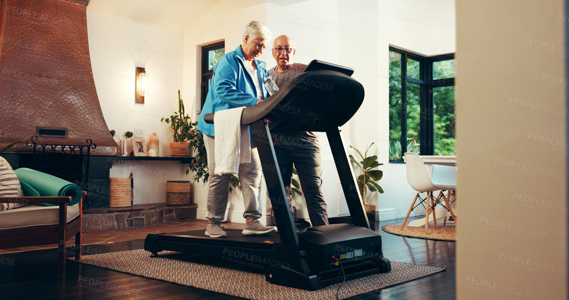 Buy stock photo Elderly couple, treadmill and help for fitness in home, walk and support with training in retirement. Senior man, woman and discussion with gym equipment, machine and steps with exercise in house