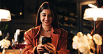 Smile, woman and phone with texting in restaurant for online dating app, dinner planning and chat. Night, wine and person with smartphone in diner for waiting, social networking and typing location