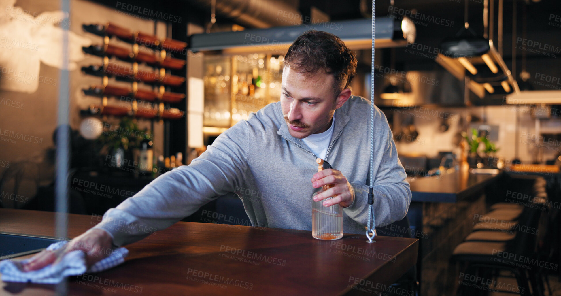 Buy stock photo Pub, bartender and cleaning with cloth for hygiene, dust and service for drinks at restaurant. Man, owner and check for dirt with spray bottle, shine and cafe with inspection at small business