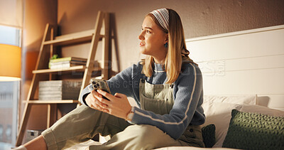 Buy stock photo Phone, smile and thinking with girl in bedroom of home for college or university communication. App, education and ideas with student sitting on bed to check text message for class or course schedule