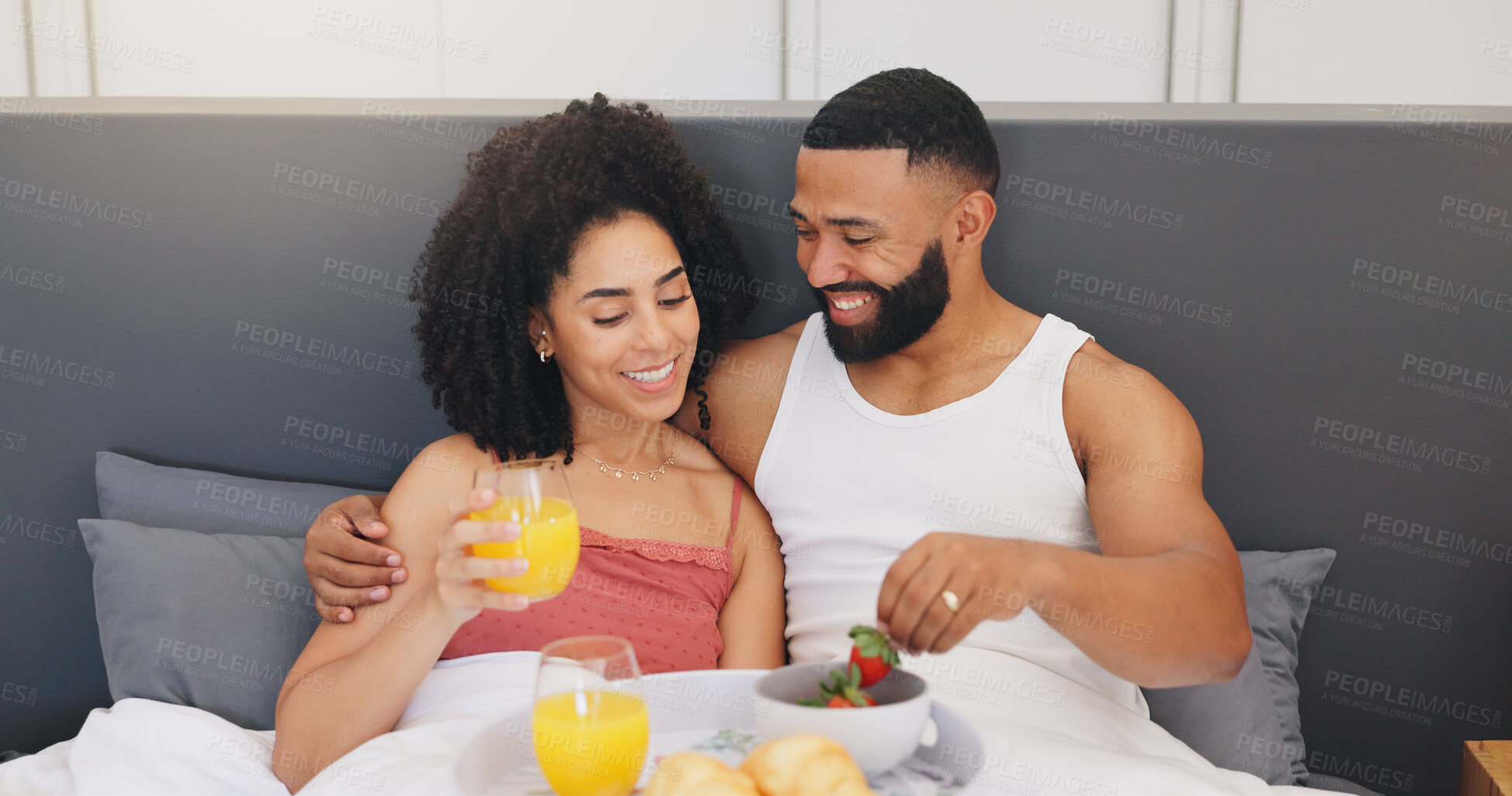 Buy stock photo Happy couple, relax and breakfast with orange juice or strawberries in bed for healthy diet in home. Man, woman or lovers with smile in bedroom for snack, nutrition or natural organic fruit in house
