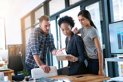 Buy stock photo Shot of a group of colleagues trying to solve something on a digital tablet at work