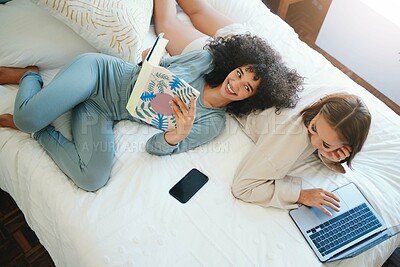 Buy stock photo Laptop, morning and a lesbian couple relax in bed while together in their home on the weekend. Reading, computer and book with happy lgbt woman with her girlfriend in the bedroom from above for love