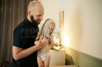 Buy stock photo Children, clothes and a father dressing his baby in pajamas in the nursery of their home for bedtime. Family, kids and a young male parent changing the clothing of his infant child in the house