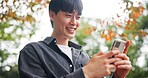 Smile, man and relax with phone at park for travel guide, communication and location directions. Happy, person and mobile for contact, abroad chat and vacation information of morning commute in Japan