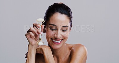 Buy stock photo Beauty, derma roller and smile of woman in studio for antiaging cosmetics or dermatology. Gua sha, massage and skincare with happy person isolated on gray background for crystal stone face treatment