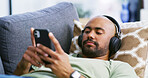 Relax, headphones and sofa with man and phone for streaming service, calm audio and ambient sound. Guided podcast, white noise and peace playlist with person in living room of home for break