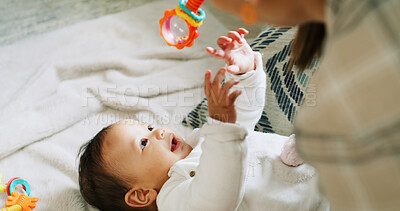 Buy stock photo Hands, baby and play with rattle on bed, mother and stimulation with color, sound and happy in home. People, mom and infant child with toys, smile or bonding with love for development in family house