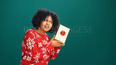Buy stock photo Curious, gift box and black woman in studio for christmas tradition, festive or surprise secret santa. Giveaway, mockup space and African person with xmas present for holiday by green background.
