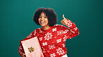 Christmas, present and thumbs up with portrait of woman in studio for celebration, motivation or success. Box, gift and smile of happy person on green background for festive holiday or tradition