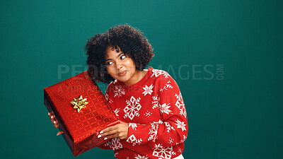 Buy stock photo Curious, present box and black woman in studio for christmas tradition, festive or surprise secret santa. Giveaway, mockup space and African person with xmas gift for holiday by green background.