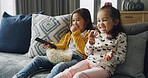 Happy girls, laughing and watching tv with popcorn on sofa for funny cartoon or movie in home. Child, siblings or sisters with smile, snack or remote for online entertainment or subscription in house