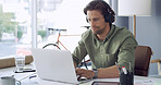 Business, headphones and laptop with man in green office for streaming sound as startup employee. Computer, music and typing with designer person in eco friendly workplace for project management