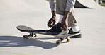 Skateboard, hands and tie shoes outdoor to prepare for sports on half pipe. Legs, person and skater tying lace with sneakers to start exercise, fashion and ready for hobby in city with streetwear