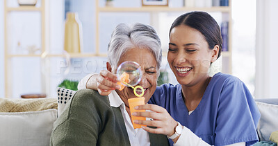 Buy stock photo Nurse, old woman and blowing bubbles with laugh, medical support and happy in retirement home. Soap toy, caregiver and elderly patient in living room for funny game with hug, bonding and healthcare