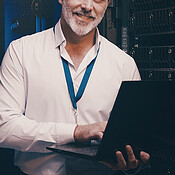 Laptop, portrait and database with man in server room for data center ...